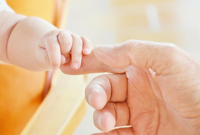 Mano di un adulto e mano di un neonato